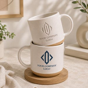 May include: Two stacked ceramic mugs with a speckled off-white finish and a natural clay base. The top mug features an embossed geometric logo and the text YOUR COMPANY LOGO. The bottom mug displays a dark blue printed geometric logo and text.