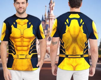 May include: A short-sleeved crew neck t-shirt featuring a graphic print of a yellow and navy blue superhero costume with a muscular torso design, a utility belt, and dark blue raglan sleeves, worn by a person in front of a castle.