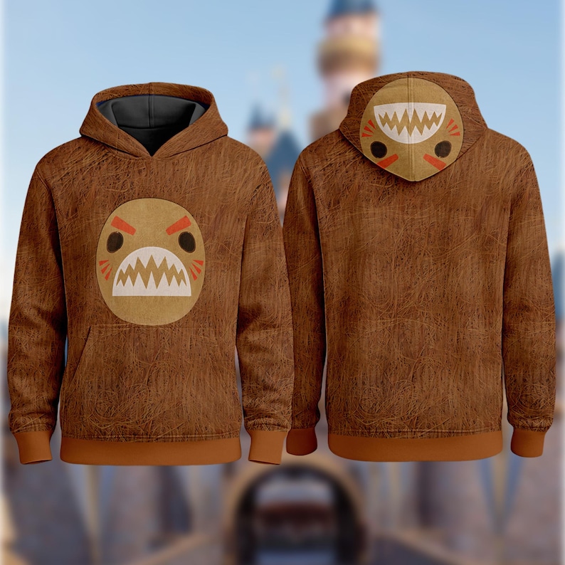 May include: Brown hoodie with a cartoon face design on the front and hood. The design features a white mouth with sharp teeth, red eyebrows, and black eyes. The hoodie has a brown body, a gray hood lining, and brown cuffs and hem.