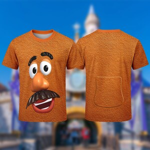 Puede incluir: Camiseta naranja de manga corta con una cara de dibujos animados con una nariz grande, bigote y boca sonriente. La parte trasera de la camiseta es naranja lisa con un dise&ntilde;o de bolsillo. La camiseta tiene un cuello naranja.