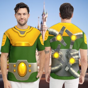 May include: A short-sleeve t-shirt featuring a green and yellow graphic print resembling a robotic suit. The front displays a yellow chest plate and a belt with a central yellow oval. The back shows four mechanical arms with glowing yellow lights.