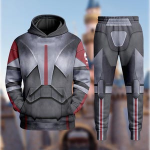 May include: A two-piece outfit featuring a hooded sweatshirt and matching sweatpants. The set is predominantly gray with red accents and a graphic design. The sweatshirt has a front pocket and a hood. The sweatpants have a drawstring waist.