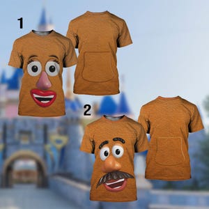 May include: Brown t-shirts featuring Mr. Potato Head's face. One shirt has a smiling face with large eyes, a pink nose, and red lips. The other shirt has a face with a mustache and a different expression. Both shirts have a pocket on the back.
