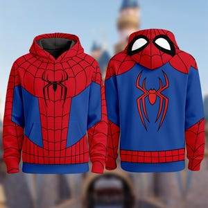 May include: A long-sleeve hooded sweatshirt featuring a red and blue color scheme with a black spiderweb pattern. The front displays a black spider emblem on the chest, while the back features a large red spider graphic and a hood with white eyes.