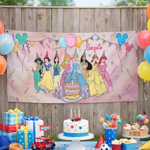 May include: A rectangular birthday banner featuring a pink background with illustrations of seven princesses wearing party hats, a birthday cake, and the name Sophia. The banner includes colorful balloons, stars, streamers, and the number 5.