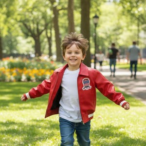Könnte beinhalten: Ein Kind in einer roten Lederjacke, einem weißen T-Shirt und einer blauen Jeans, das auf Gras rennt. Die Jacke hat einen Aufnäher auf der Brust. Das Kind trägt rote Turnschuhe. Der Hintergrund zeigt einen Park mit Bäumen und Menschen.