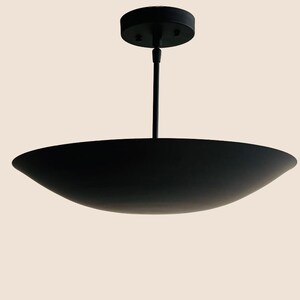 May include: A black pendant light fixture with a wide, shallow, saucer-shaped shade.