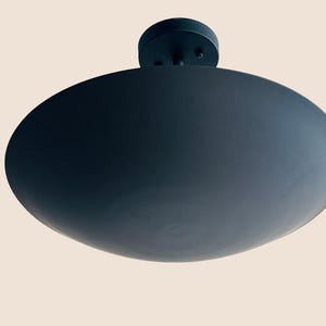 May include: A black ceiling light fixture with a large, round, flat shade.