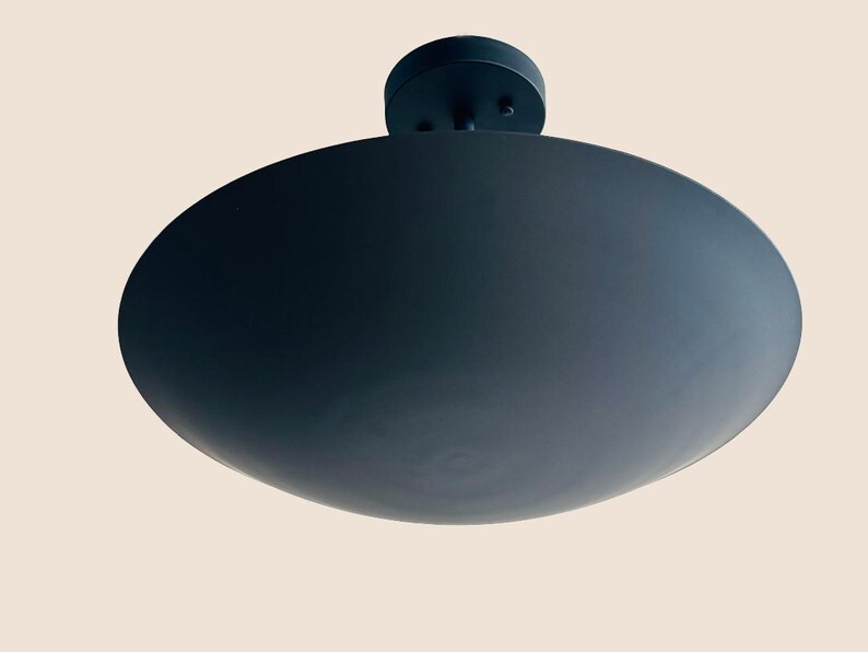 May include: A black ceiling light fixture with a large, round, flat shade.
