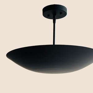 May include: A black pendant light fixture with a wide, shallow, saucer-shaped shade.