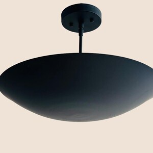 May include: A black metal ceiling light fixture with a wide, shallow, saucer-shaped shade.