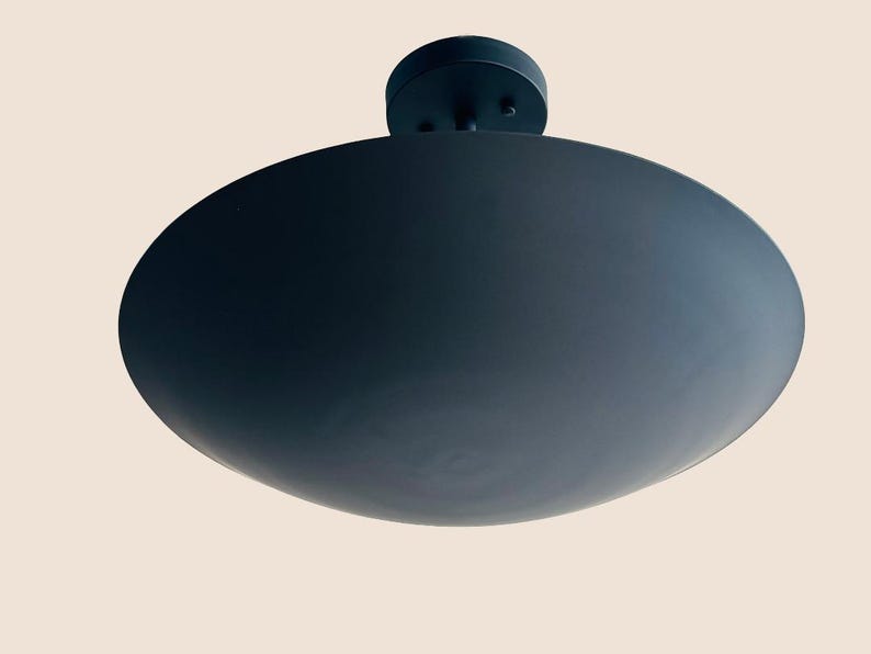 May include: A black ceiling light fixture with a large, round, flat shade.
