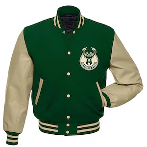 May include: Green and beige varsity jacket featuring the Milwaukee Bucks logo. The jacket has a green body, beige sleeves, and cream stripes on the collar, cuffs, and hem. It has a button-up front and two front pockets. The jacket's measurements are in centimeters.