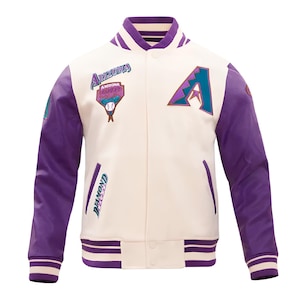 May include: Cream-colored baseball jacket with purple sleeves and accents. Features the Arizona Diamondbacks logo and team name patches. Includes a striped collar, cuffs, and hem. A classic varsity style.