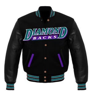 May include: Black varsity jacket with leather sleeves. The jacket features the text "DIAMONDBACKS" in teal, purple, and white. Teal and white stripes accent the collar, cuffs, and hem. The jacket has a button-up front and purple accents.