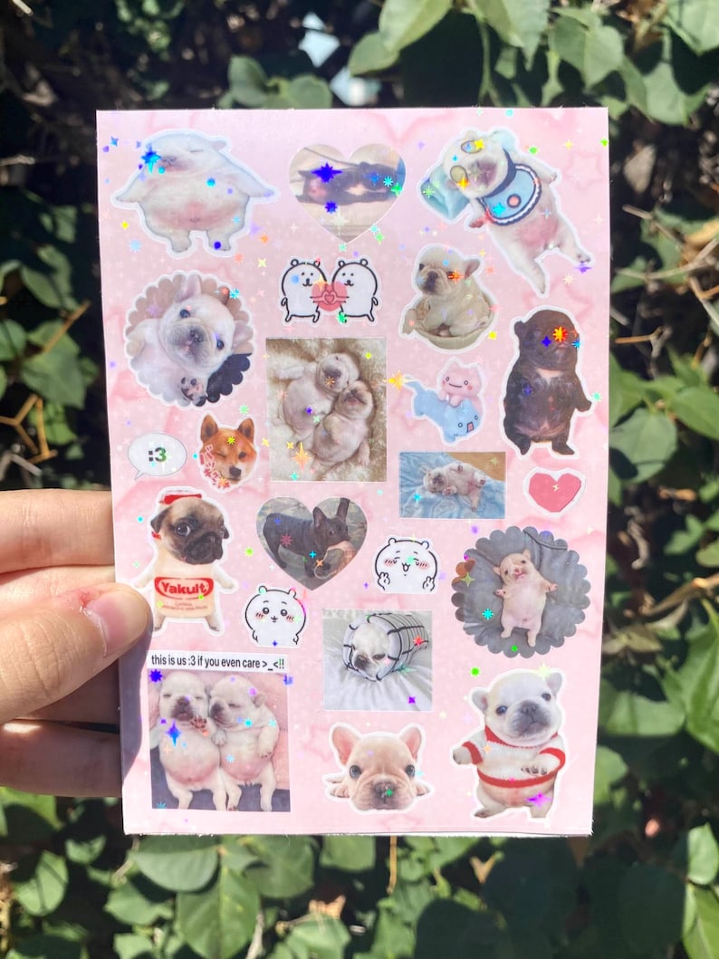 May include: A sheet of pink stickers featuring various images of puppies, cartoon characters, and hearts. Some stickers have glitter accents. Text on the sheet reads ":3" and "this is us :3 if you even care> <!!".