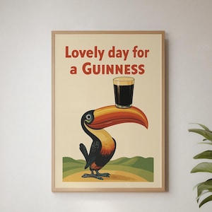 May include: A framed vintage-style poster featuring a toucan balancing a pint of Guinness. The poster has the text "Lovely day for a Guinness" in red. The toucan is black, orange, and yellow, set against a cream background.