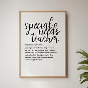 May include: A framed print with the words "special needs teacher" in a stylish font. The definition below describes the role of a special needs teacher. The print hangs above a white armchair in a well-lit room with a wooden floor.