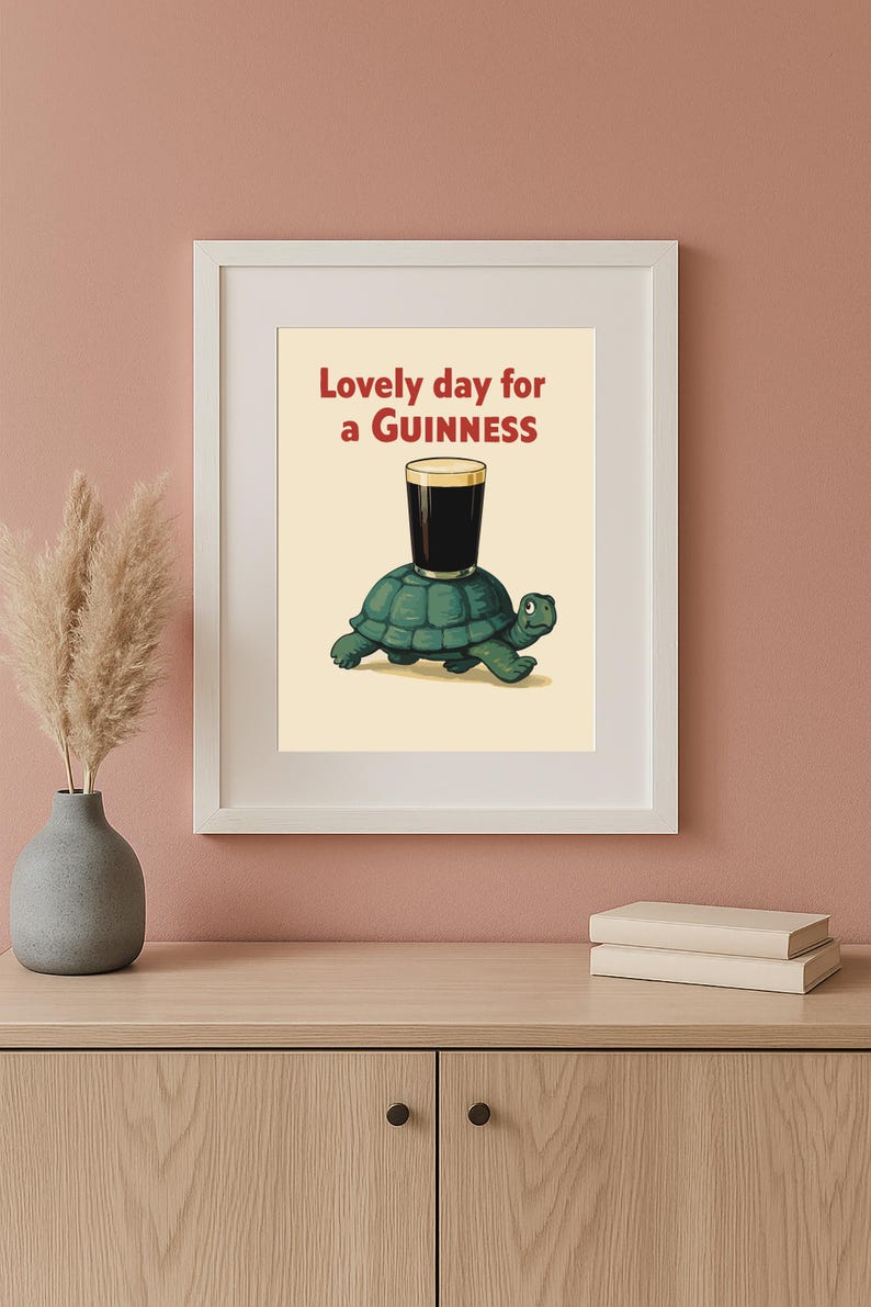 Puede incluir: Impresi&oacute;n enmarcada con una tortuga de dibujos animados que lleva una pinta de Guinness. El texto rojo dice "Lovely day for a Guinness". La imagen tiene un fondo crema y est&aacute; en un marco blanco.