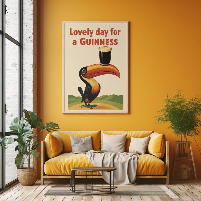 May include: A framed vintage-style poster with a toucan carrying a pint of Guinness on its beak. The poster reads "Lovely day for a Guinness" in red text. The toucan is black, orange, and yellow, set against a cream background.