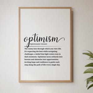 Può includere: Una stampa incorniciata con la definizione di "ottimismo" in testo nero su sfondo bianco. La definizione include la pronuncia della parola e una descrizione del suo significato. La cornice è di colore marrone chiaro.