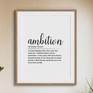 May include: A framed print with the word "ambition" in elegant script. Below, a definition explains ambition as drive and growth. The print is in a wooden frame, suitable for home or office decor.
