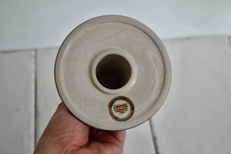 Puede incluir: Portavelas de cer&aacute;mica blanca con base redonda y un agujero central para una vela. La base tiene un logotipo marr&oacute;n que dice "DANSK INTERNATIONAL DENMARK".