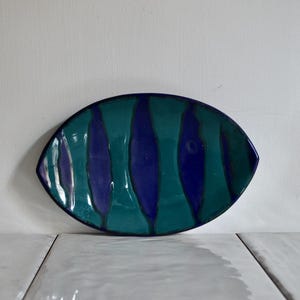 May include: A blue and green ceramic dish with a striped pattern. The dish is oval shaped and has a glossy finish.