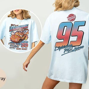 K&ouml;nnte beinhalten: Hellblaues T-Shirt mit einem Lightning McQueen-Motiv aus dem Film Cars. Das Frontdesign enth&auml;lt den Text "Get Loud Lightning McQueen" und "Need for Speed 95 Race Ready". Auf der R&uuml;ckseite ist eine gro&szlig;e "95" mit dem Text "Lightning McQueen" abgebildet.