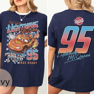 K&ouml;nnte beinhalten: Marineblaues T-Shirt mit Lightning McQueen aus Cars. Die Vorderseite zeigt das Auto, Flammen und den Text "Street Legend Lightning McQueen Need for Speed Race Ready 95". Auf der R&uuml;ckseite steht "95" und "Lightning McQueen".