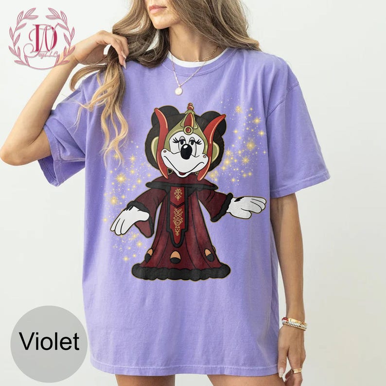 Puede incluir: Camiseta de color violeta con un personaje de dibujos animados con un atuendo rojo y dorado. El gr&aacute;fico incluye un personaje con cara blanca, ojos negros y un tocado rojo y dorado. La camiseta tiene un corte holgado y mangas cortas.