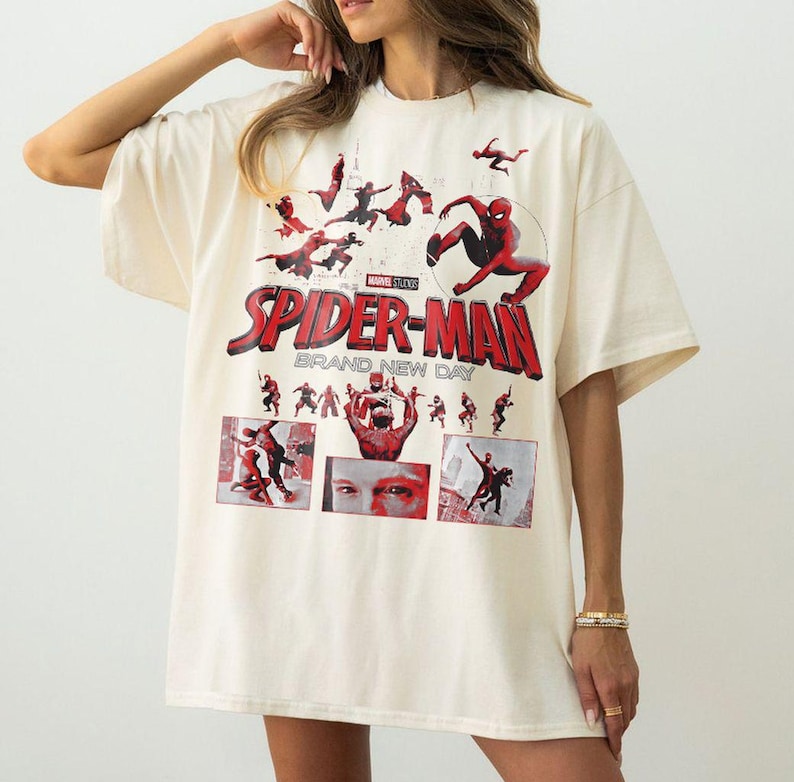 May include: Cream-colored Spider-Man t-shirt featuring the Marvel Studios logo and the words "Spider-Man Brand New Day" in red. The shirt has multiple images of Spider-Man in action.