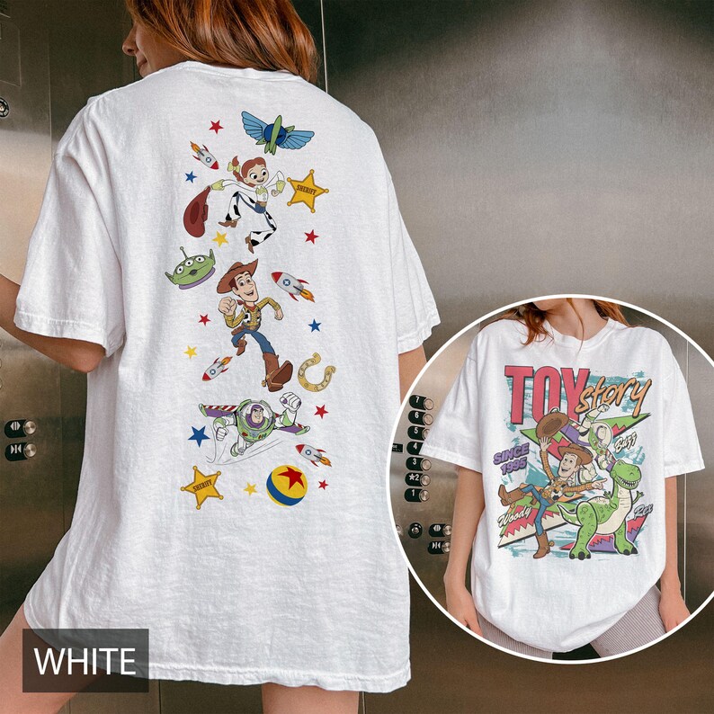 May include: White t-shirt with a Toy Story design. The back displays Woody, Buzz Lightyear, Jessie, and other characters with rockets and stars. The front has the Toy Story logo and characters.