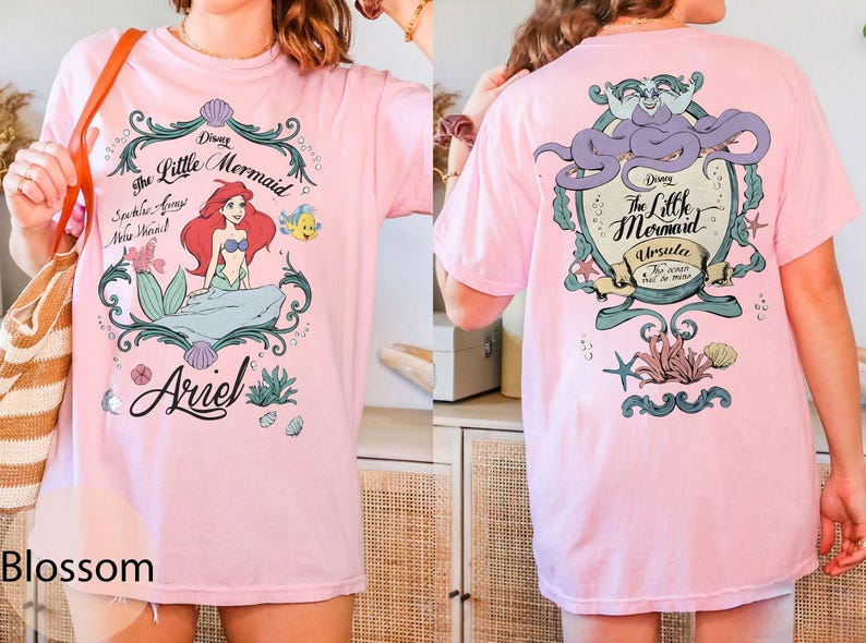 May include: A light pink t-shirt featuring a graphic of Ariel from Disney's The Little Mermaid. The front design includes Ariel, Flounder, and the text "The Little Mermaid". The back features Ursula. The shirt is a comfortable, casual style.