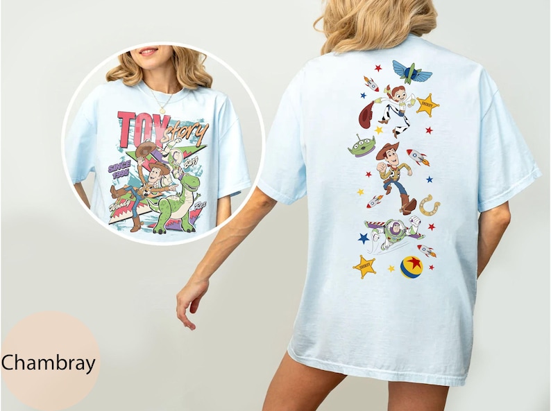 May include: Pale blue t-shirt with a Toy Story graphic. The front has the film's title and characters, the back features a vertical design of characters and rockets. A relaxed, casual top.
