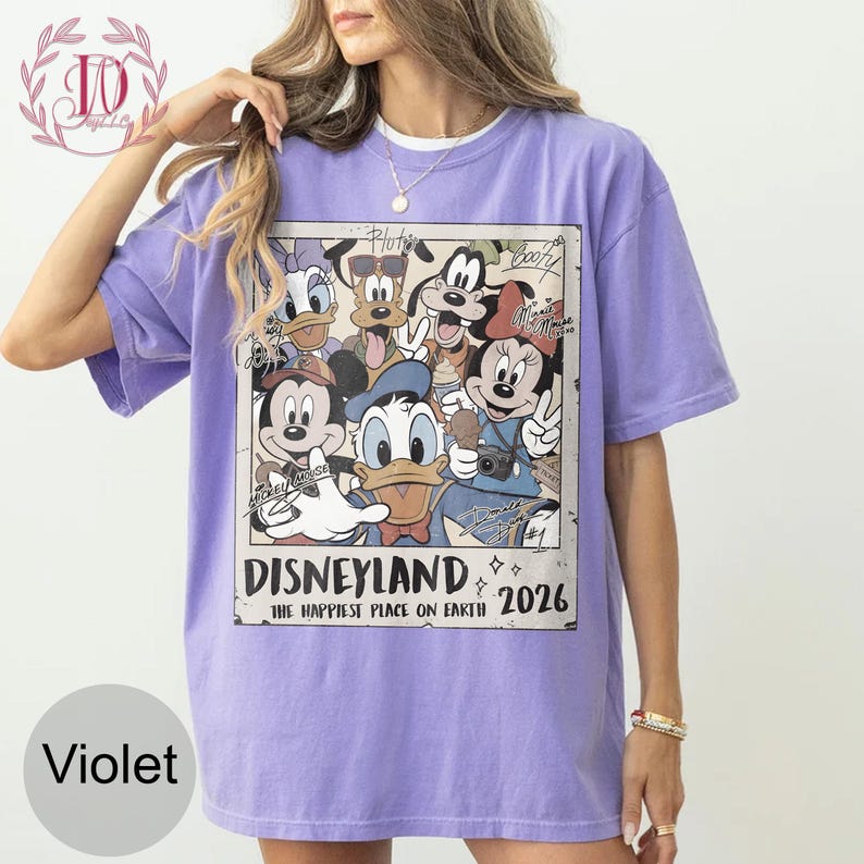 K&ouml;nnte beinhalten: Violettes T-Shirt mit einem Vintage-Disneyland-Motiv. Das Design zeigt Zeichentrickfiguren wie Mickey und Minnie Mouse. Der Text "Disneyland, The Happiest Place on Earth, 2026" ist ebenfalls auf dem T-Shirt zu sehen.