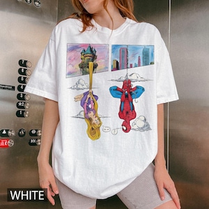 Peut inclure: T-shirt blanc avec un motif de bande dessin&eacute;e. Le graphisme pr&eacute;sente une princesse et Spider-Man dans des cases s&eacute;par&eacute;es. Le t-shirt a une coupe d&eacute;contract&eacute;e et des manches courtes.
