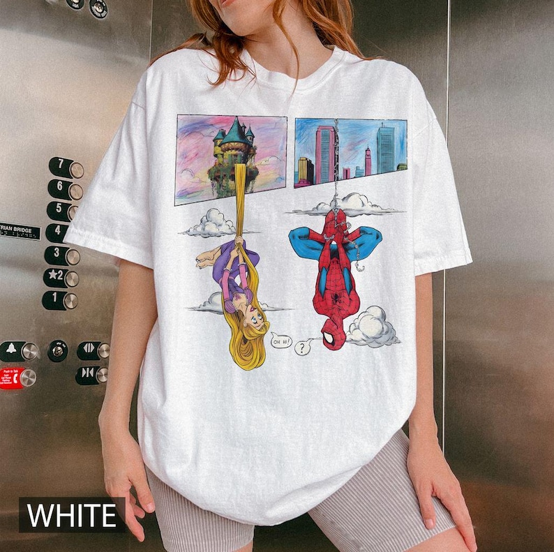 Peut inclure: T-shirt blanc avec un motif de bande dessin&eacute;e. Le graphisme pr&eacute;sente une princesse et Spider-Man dans des cases s&eacute;par&eacute;es. Le t-shirt a une coupe d&eacute;contract&eacute;e et des manches courtes.
