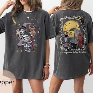 Puede incluir: Camiseta gris oscuro con un gr&aacute;fico colorido de personajes de "Pesadilla antes de Navidad" en la parte delantera y trasera. El gr&aacute;fico frontal incluye a Jack Skellington y otros personajes. El gr&aacute;fico trasero tiene una luna y el texto "The Nightmare Before Christmas."