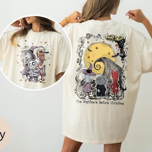 Puede incluir: Camiseta de color marfil con un gr&aacute;fico de "Pesadilla antes de Navidad". La parte delantera muestra los personajes, mientras que la parte trasera muestra una luna llena, una colina arremolinada y m&aacute;s personajes. El texto "The Nightmare Before Christmas" est&aacute; impreso debajo.