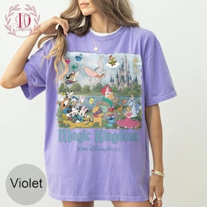 May include: A violet short-sleeve t-shirt featuring a graphic print of various Disney characters, a castle, and the text Magic Kingdom Walt Disney World. The design includes Dumbo, Ariel, Mickey Mouse, Minnie Mouse, Stitch, and other figures.