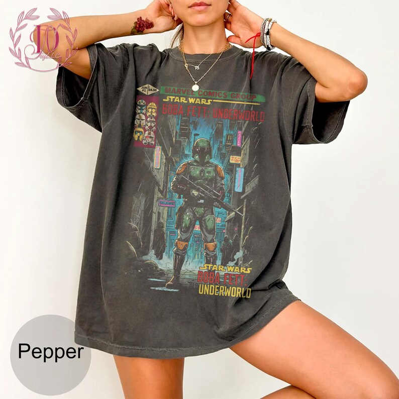 May include: Dark gray t-shirt featuring a Star Wars comic book cover with Boba Fett. The graphic includes the text "Marvel Comics Group Star Wars Boba Fett Underworld" in red, green, and yellow. The shirt has short sleeves and a relaxed fit.