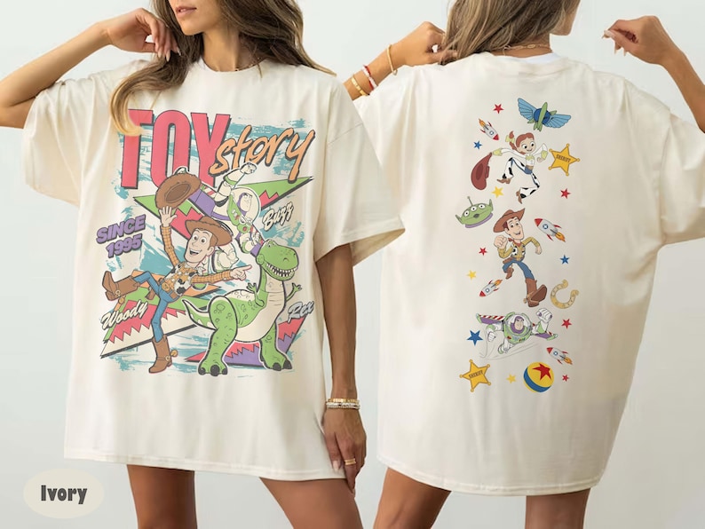 May include: Ivory-coloured t-shirt with the words "Toy Story" and cartoon characters Woody, Buzz, Rex, and others. The front design includes the text "Since 1995". The back of the shirt has a vertical design with more Toy Story characters and elements.
