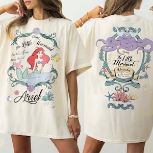 May include: A white ceramic mug with a black handle and the text "But First, Coffee" in a black, handwritten-style font. The mug is on a white surface.