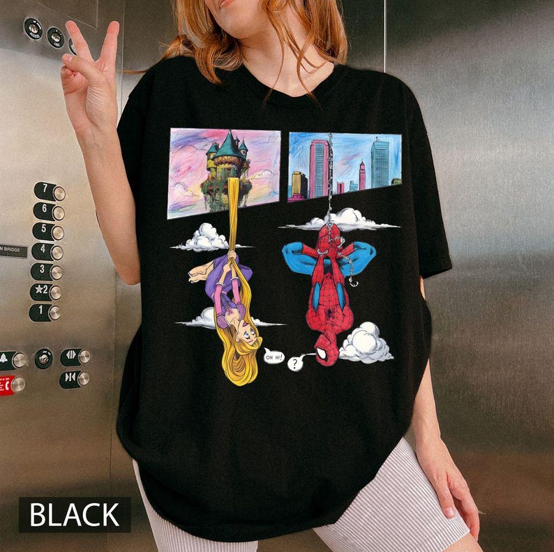 Peut inclure: T-shirt noir avec un dessin anim&eacute; de Raiponce et Spider-Man suspendus &agrave; l'envers. Raiponce est suspendue par ses longs cheveux dor&eacute;s, et Spider-Man est suspendu &agrave; une toile d'araign&eacute;e. Le mot "BLACK" est imprim&eacute; en bas.