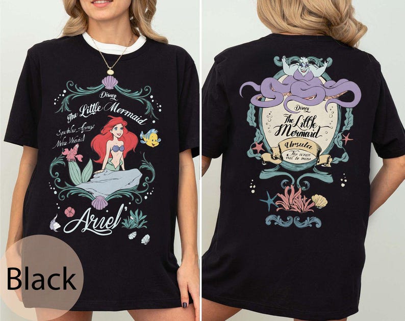 May include: Black t-shirt featuring a colorful graphic from Disney's The Little Mermaid. The front design includes Ariel, Flounder, and text. The back features Ursula and more text. The shirt has a white collar.