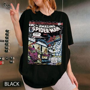 May include: Black t-shirt featuring a comic book cover of The Amazing Spider-Man. The graphic shows Spider-Man in action against the Green Goblin. The shirt also has the text "MARVEL COMICS GROUP" and "BLACK" at the bottom.