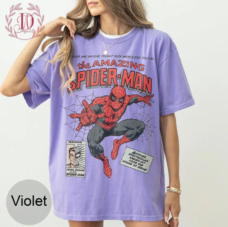 Puede incluir: Camiseta violeta con un dise&ntilde;o de c&oacute;mic de Spider-Man. El dise&ntilde;o incluye el texto "the AMAZING SPIDER-MAN" e ilustraciones del superh&eacute;roe. El texto adicional incluye "Peter Parker alias Spider-Man".