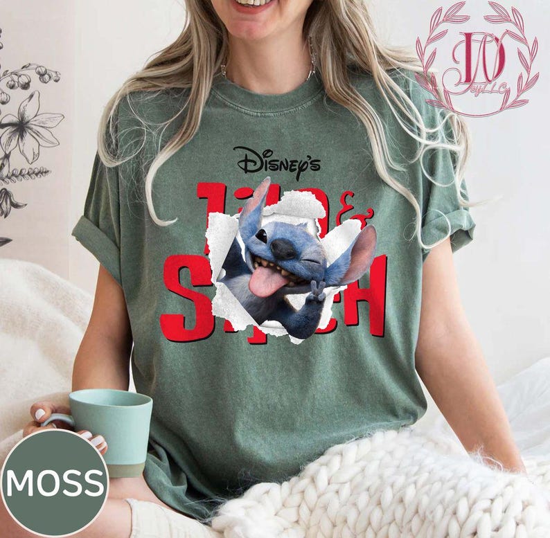 Op de afbeelding: Groen t-shirt met de tekst "Disney's Lilo & Stitch" in het rood, met een afbeelding van Stitch die door een gescheurd papiereffect breekt. Het shirt heeft korte mouwen en een relaxte pasvorm.