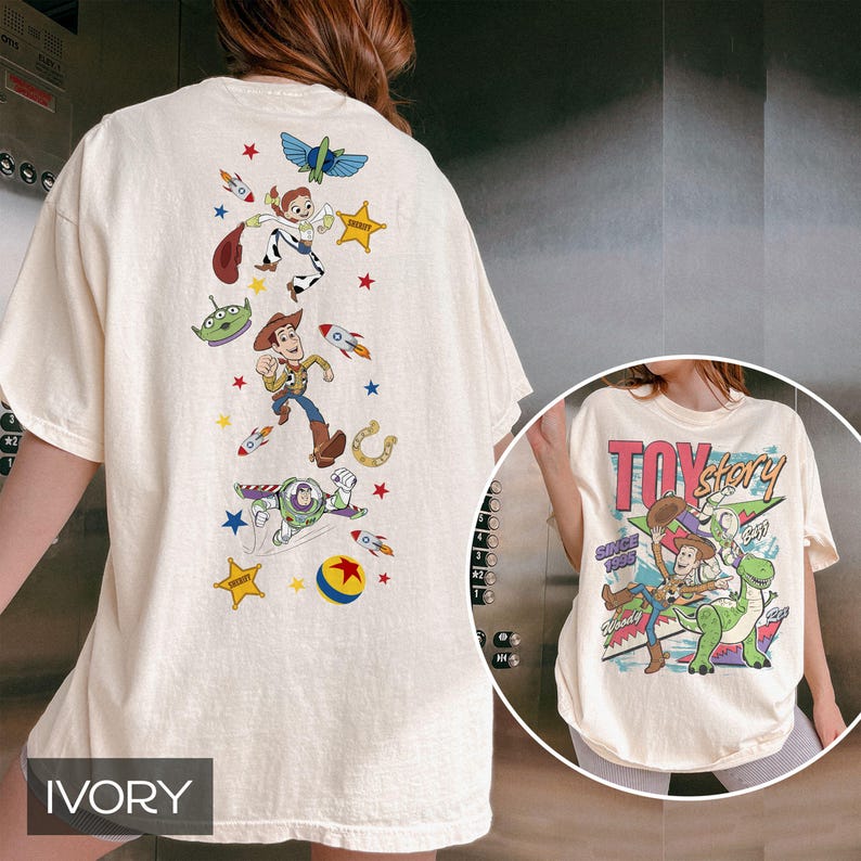 May include: Ivory t-shirt with a colourful cartoon design and the text "TOY STORY" with "SINCE 1995". The back of the shirt features Woody, Buzz Lightyear, Jessie, and other characters from the film.